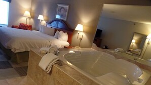 A hotel room with a large bathtub, a bed with white linens, two bedside lamps, and a framed picture on the wall. - Hampton Inn Bowling Green (Bowling Green)