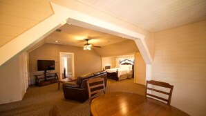 A cozy attic bedroom with a wooden ceiling, a bed, a TV, and a dining table. - Vizcaya (Sacramento)