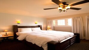 A hotel room with a large bed, a ceiling fan, two bedside lamps, and a window with curtains. - Vizcaya (Sacramento)