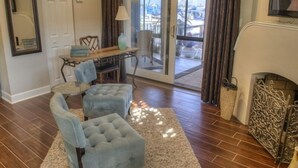 A living room with a fireplace, a dining area with a table and chairs, and a view through a glass door to the outside. - Pasa Tiempo Private Waterfront Resort - Adults Only (St. Pete Beach)