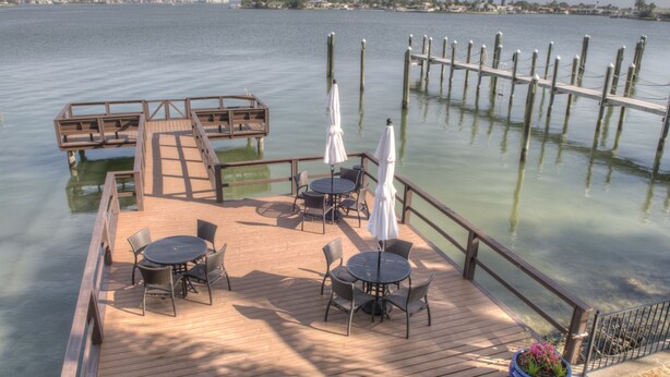 A wooden deck with outdoor seating and a view of the water. - Pasa Tiempo Private Waterfront Resort - Adults Only (St. Pete Beach)
