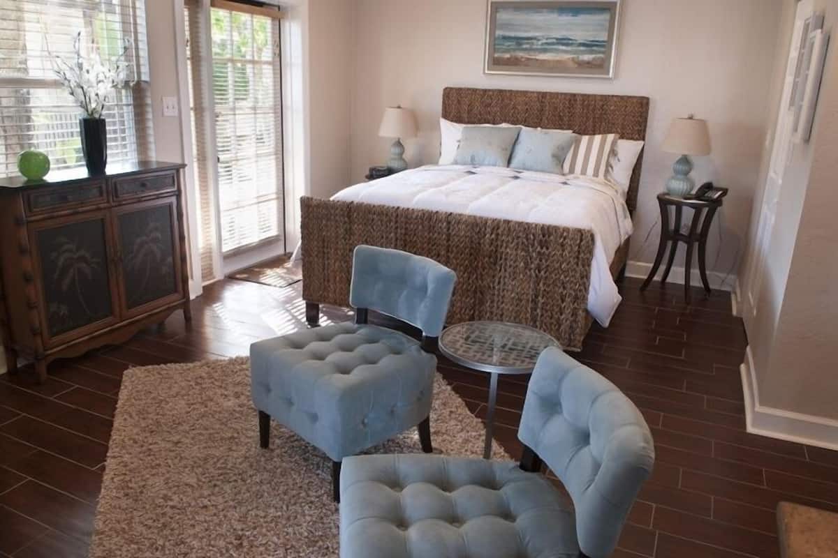 A bedroom with a large bed, two bedside tables with lamps, a small round table, and two armchairs.