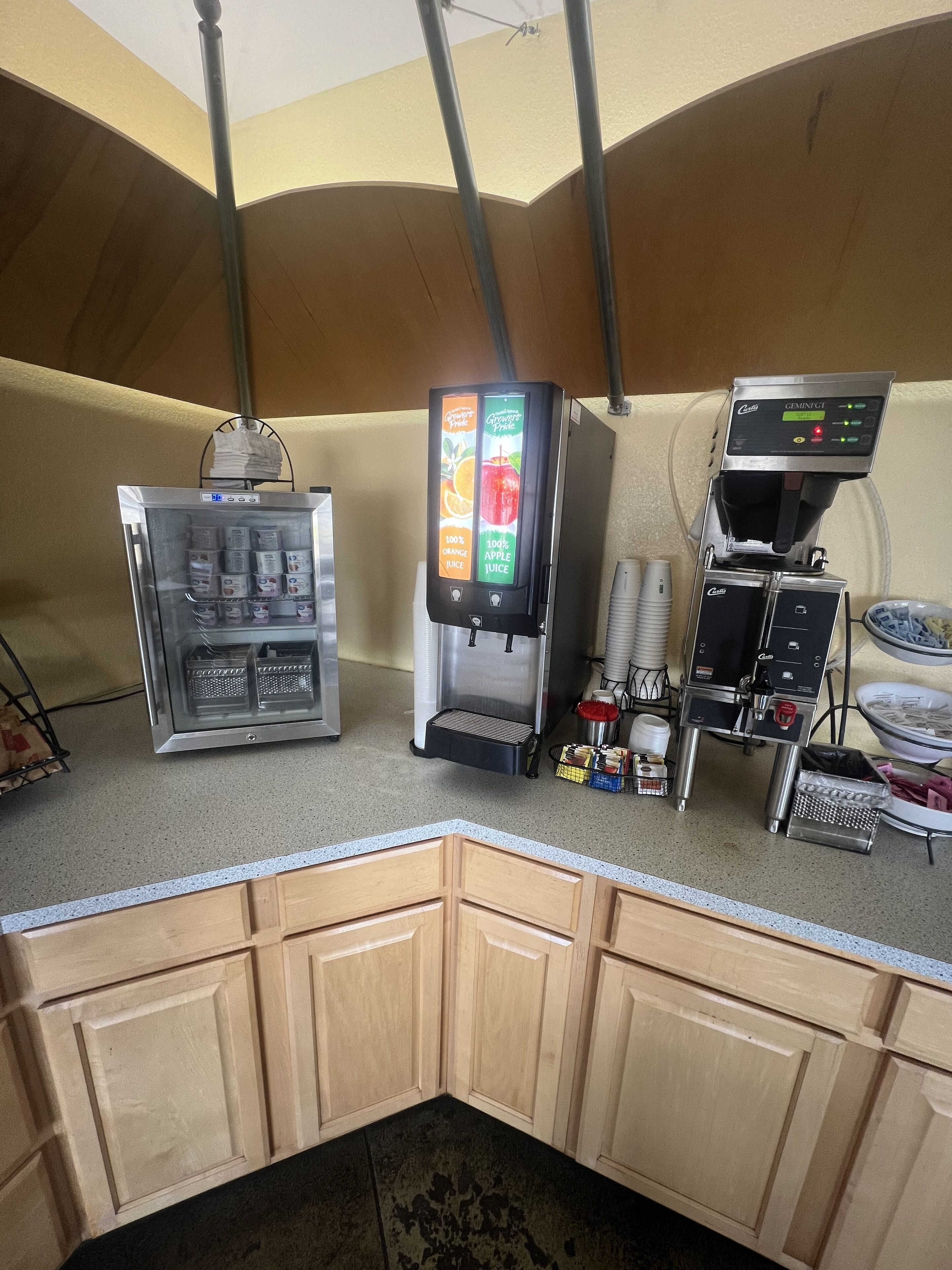 A self-service beverage station with a refrigerated drink dispenser, a juice dispenser, and a coffee machine.