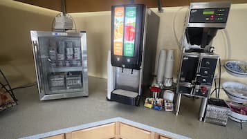 A self-service beverage station with a refrigerated drink dispenser, a juice dispenser, and a coffee machine.