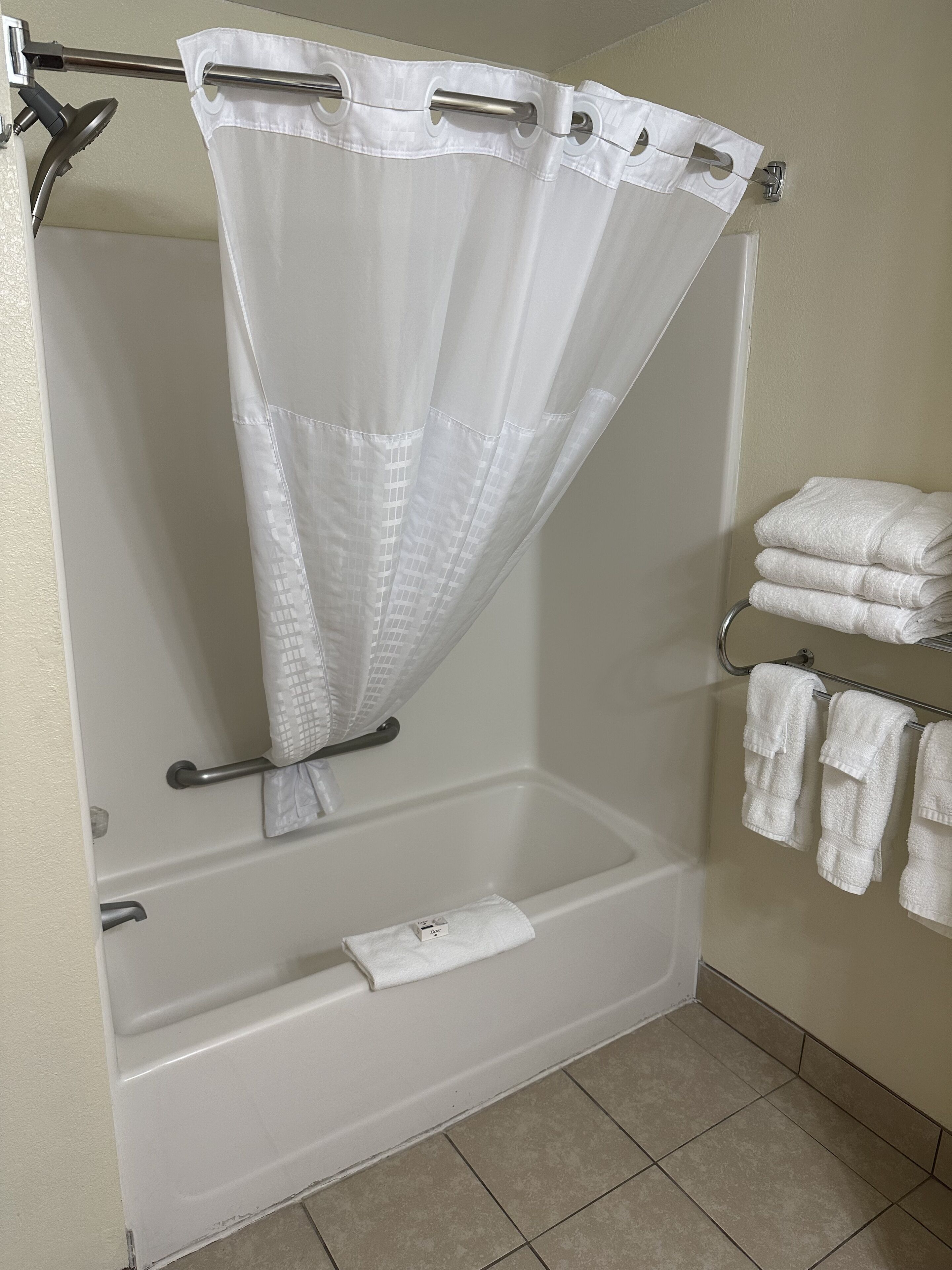 Une salle de bain avec un rideau de douche, une baignoire et un porte-serviettes avec des serviettes.