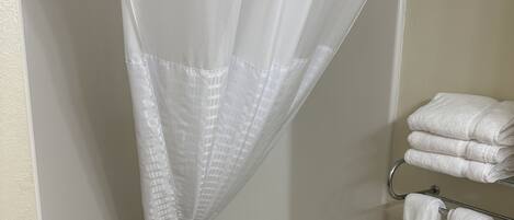 Une salle de bain avec un rideau de douche, une baignoire et un porte-serviettes avec des serviettes.