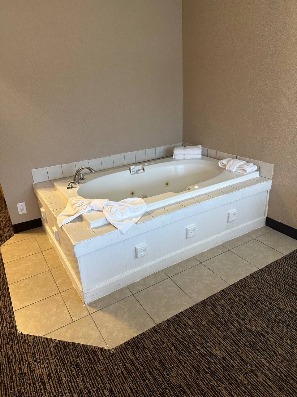 Una bañera grande y rectangular con ducha integrada, un perchero y un panel de control.