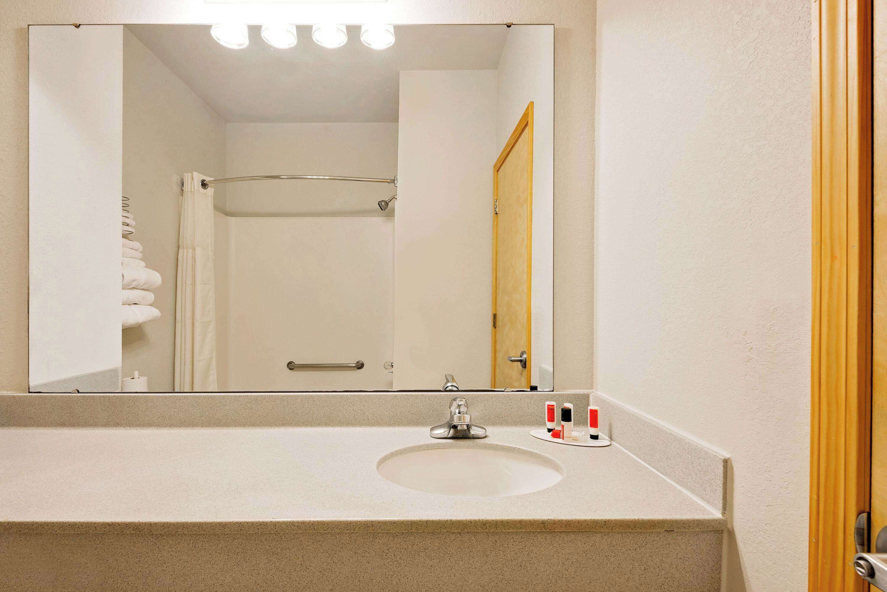 Un baño con lavamanos, espejo y toallero.