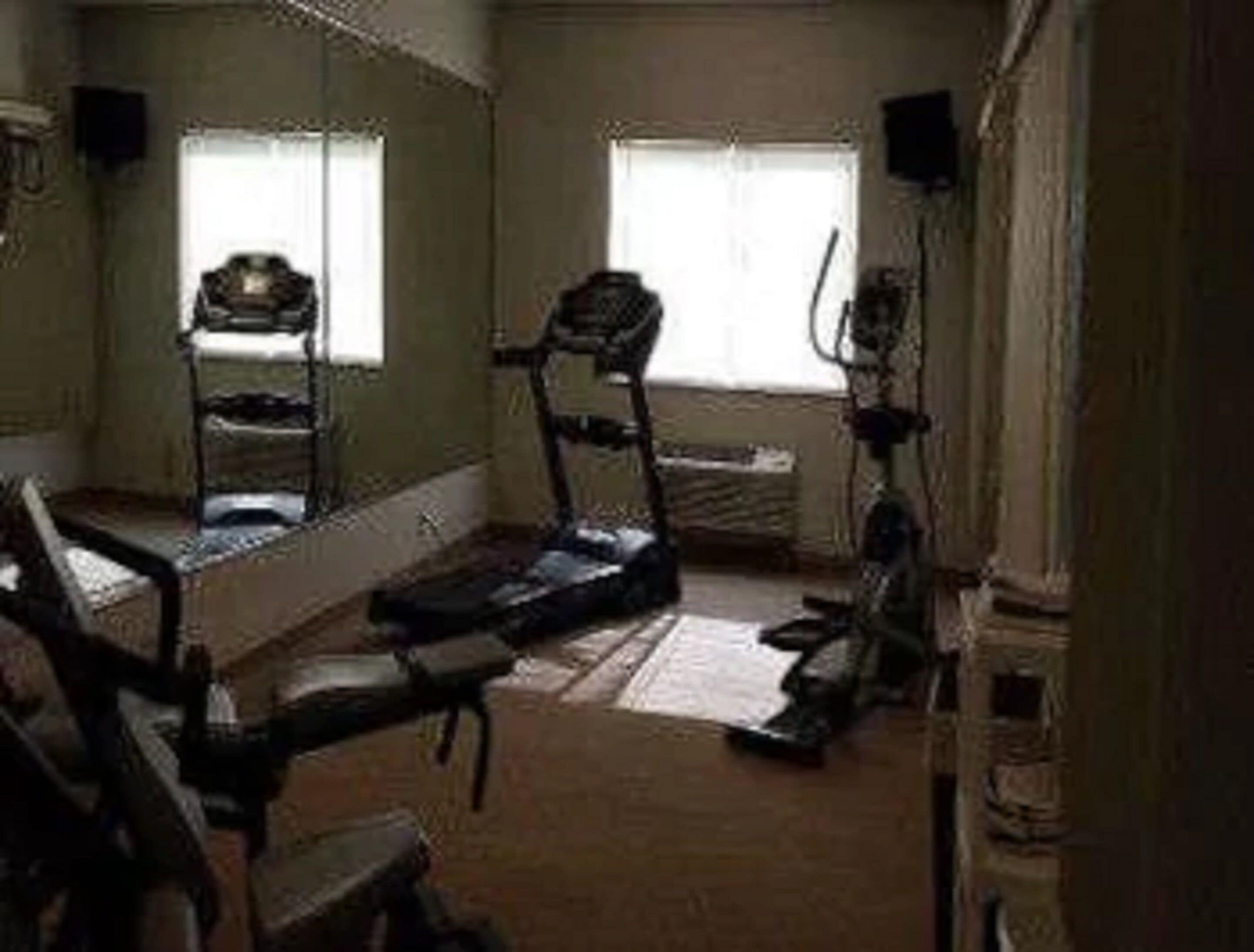 Habitación con una caminadora, un escritorio y un espejo grande.