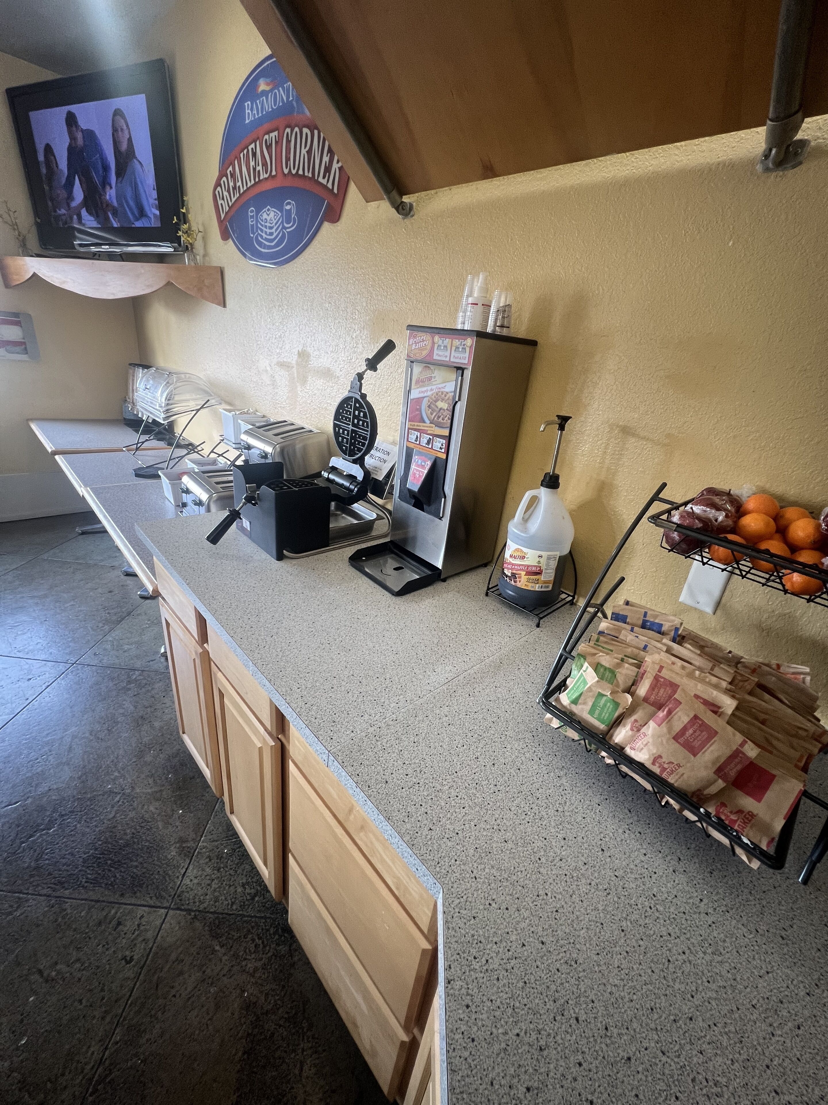 A breakfast counter with a waffle maker, coffee machine, and a sign for 'Breakfast Corner'.