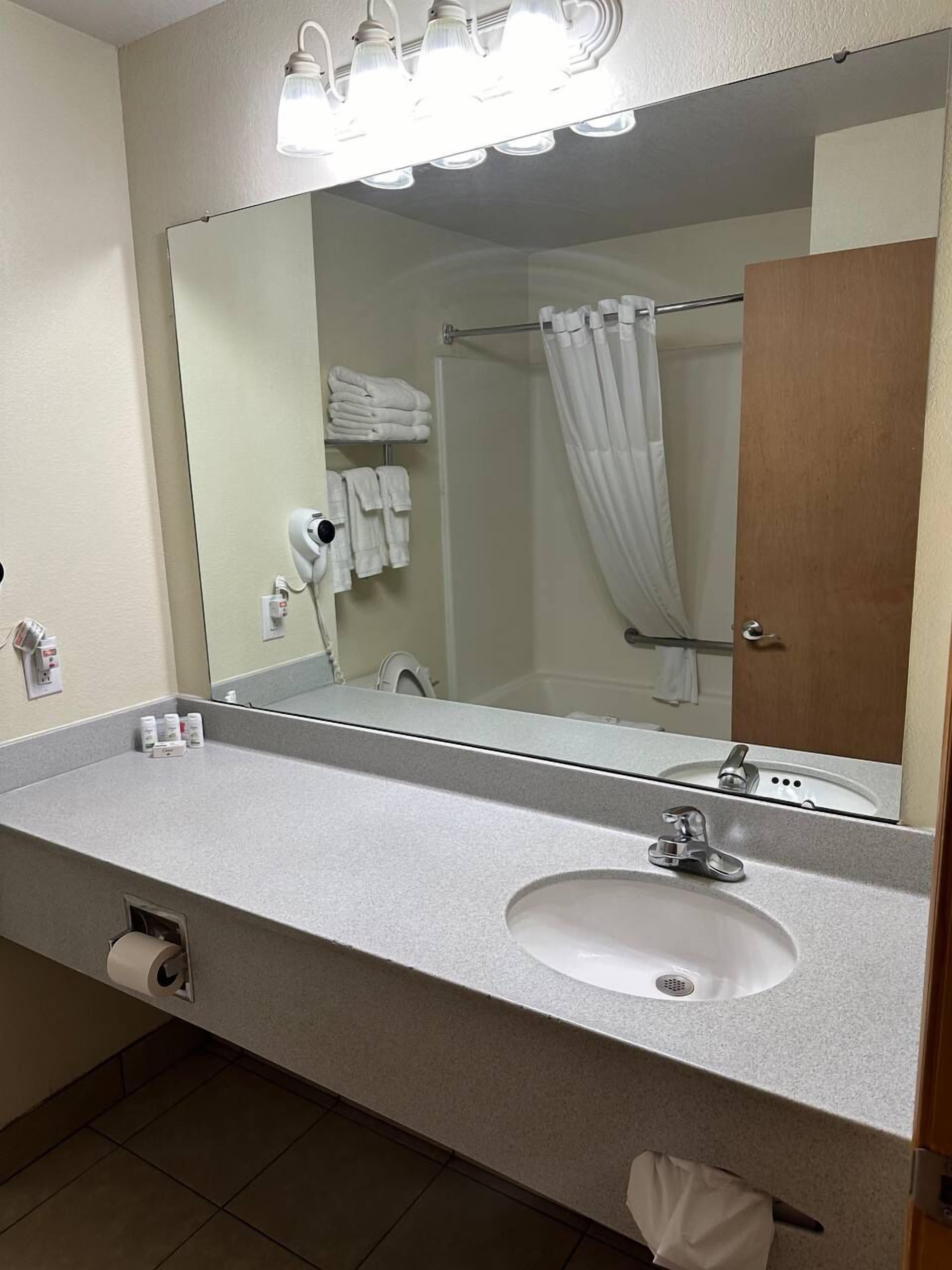 A bathroom with a sink, mirror, towel rack, and a shower curtain.