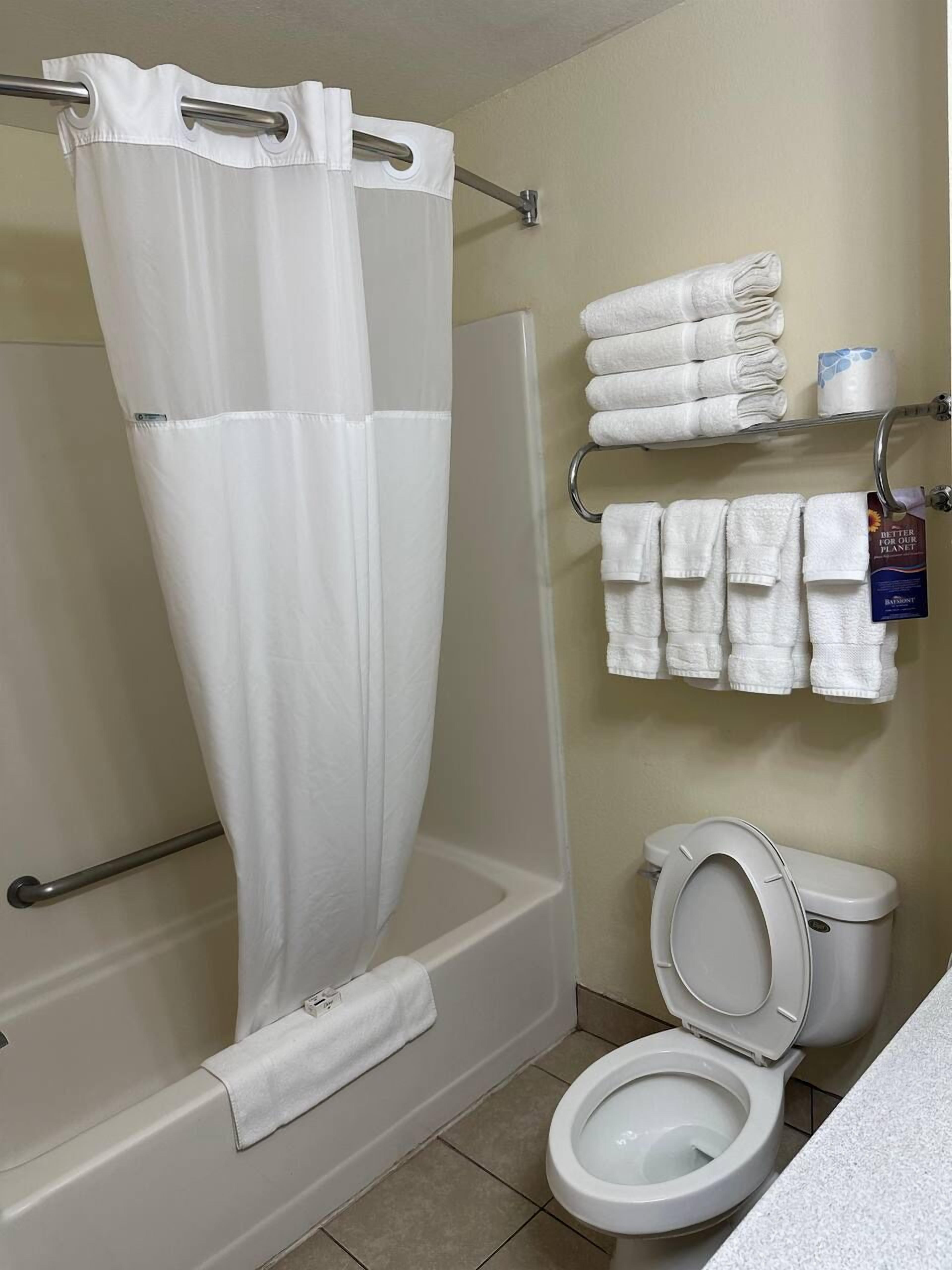 A bathroom with a shower curtain, a toilet, and a towel rack with folded towels.