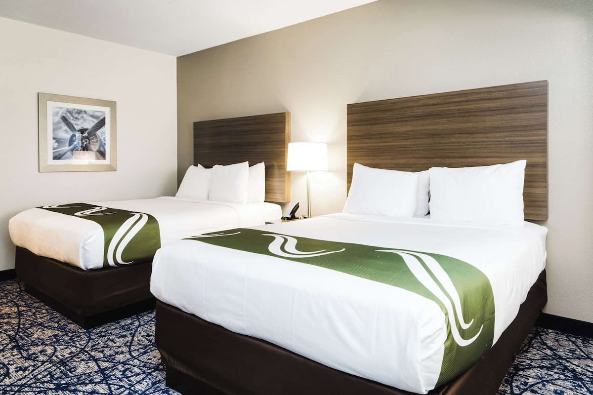 Two double beds with wooden headboards, white bedding, and a patterned carpet.