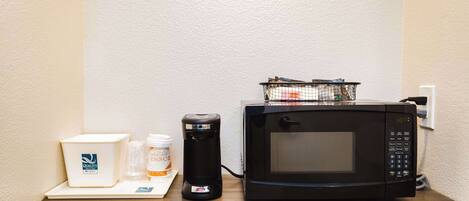 A microwave, a coffee maker, and a box labeled "Quality" on a wooden counter.
