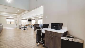 Een ruime kantoorruimte met een modern design, met een bureau, een computer, een prullenbak en een zithoek met stoelen.