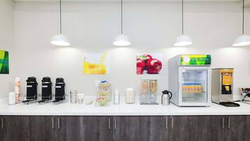 A breakfast bar with coffee makers, a waffle maker, and a refrigerator.
