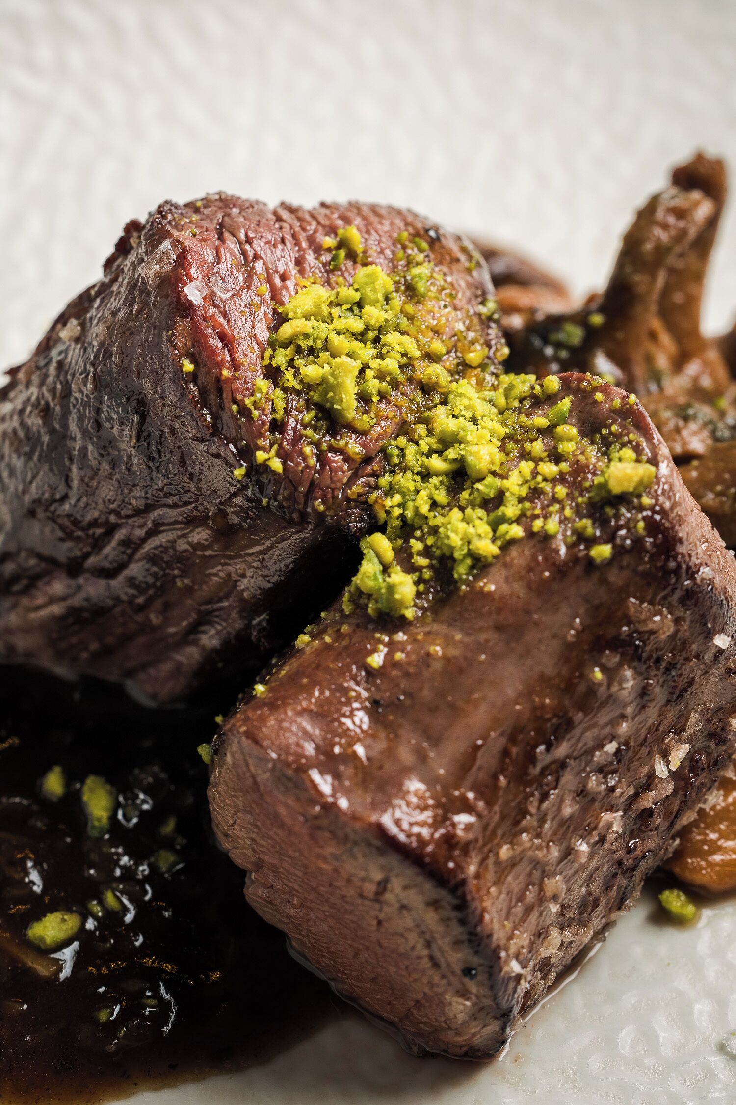 Une vue rapprochée d’un steak surmonté d’une garniture verte, probablement des herbes ou des épices.