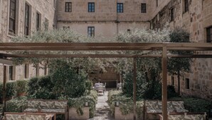 A courtyard with a pergola, seating, and a view of a stone building.