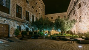 Un patio con edificios de piedra, mobiliario exterior y árboles.