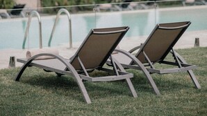 Two lounge chairs by a pool with a view of a historic building in the background.