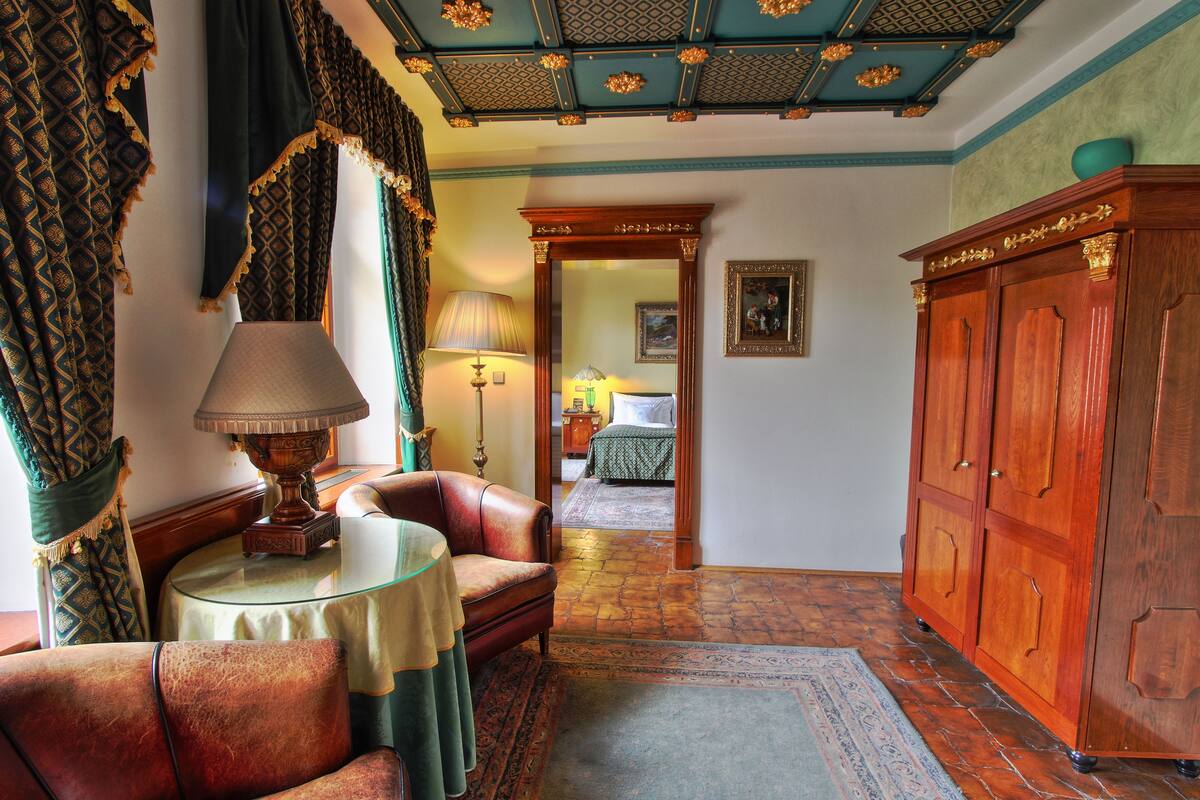 A room with a leather sofa, a table with a lamp, a wooden cabinet, and a patterned rug.