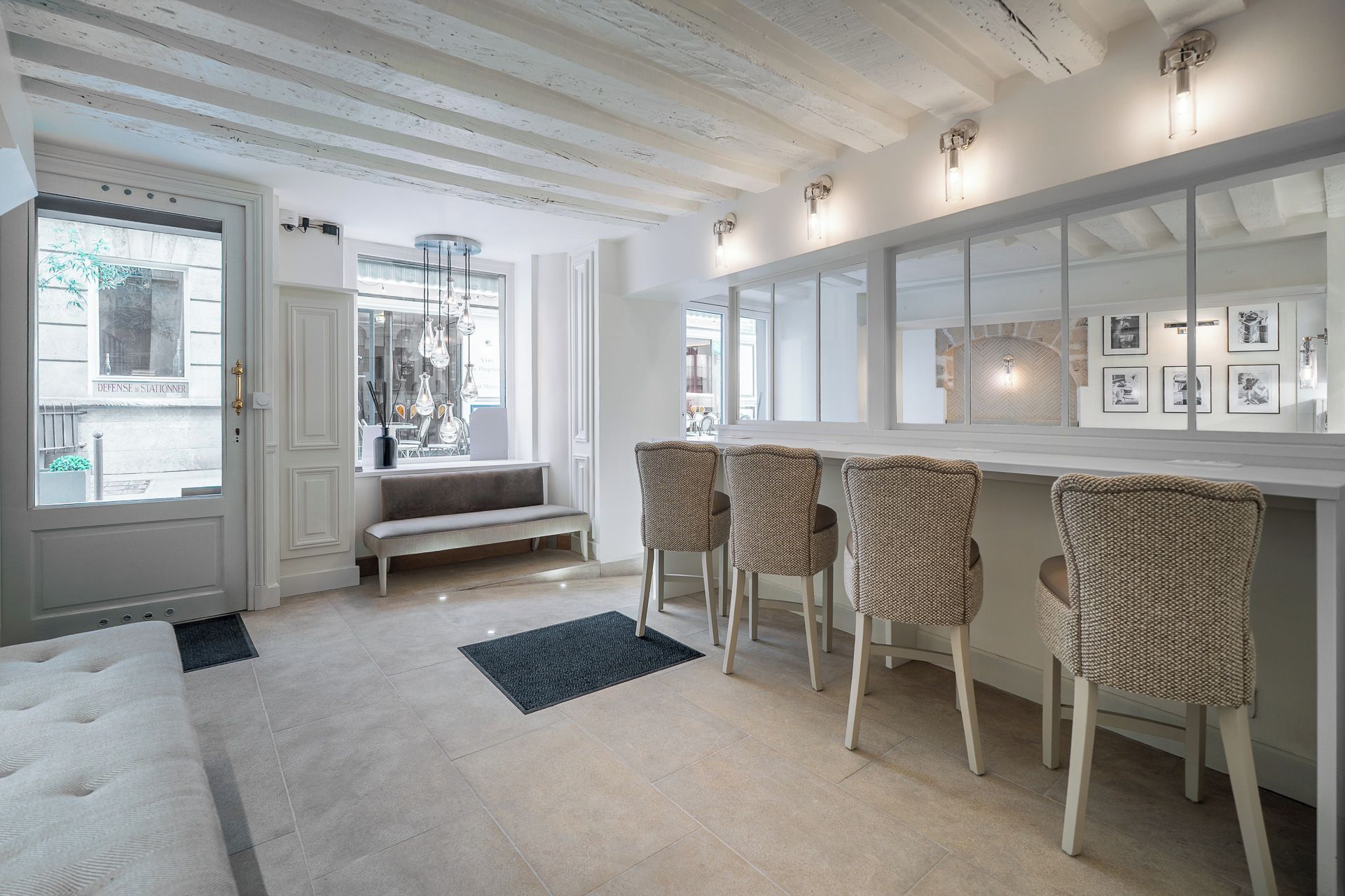 A modern interior with a bench, bar stools, and a large mirror.