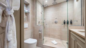 A modern bathroom with a glass-enclosed shower, a white toilet, and a glass shower door.