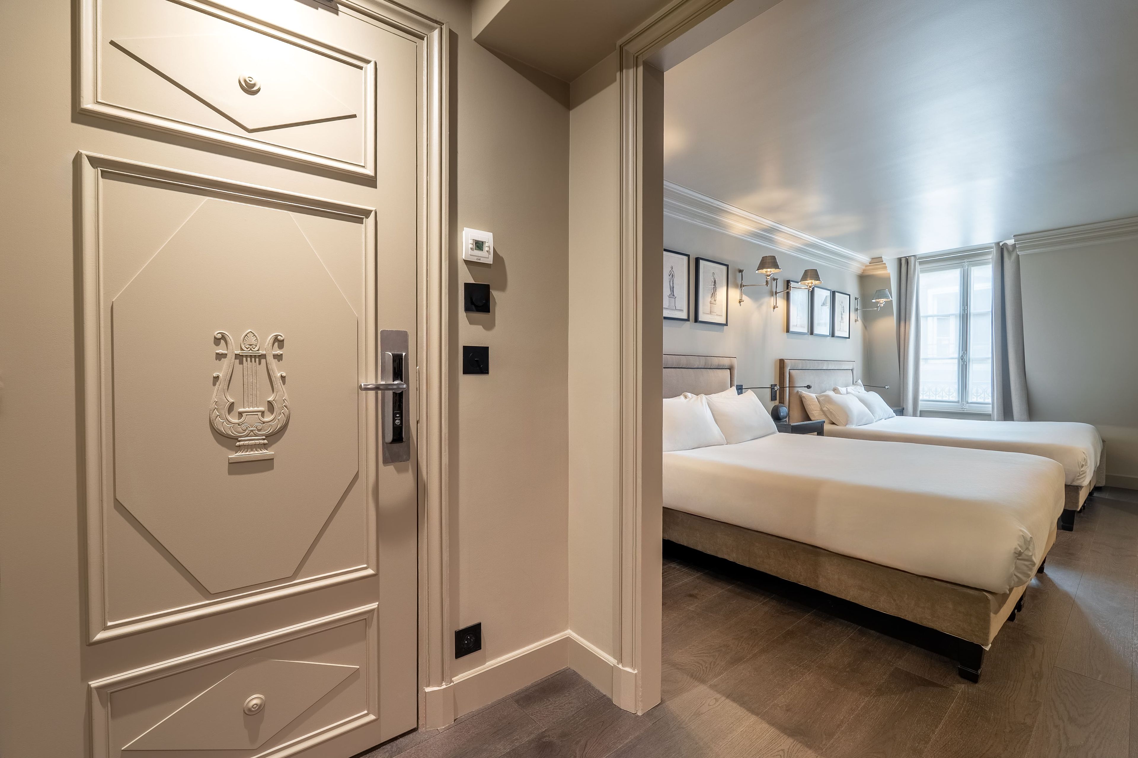 Een hotelkamer met een groot bed, twee nachtkastjes, een kledingkast en een deur met een decoratieve handgreep.