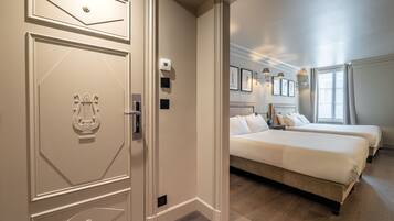 Habitación de hotel con una cama grande, dos mesitas de noche, un armario y una puerta con pomo decorativo.