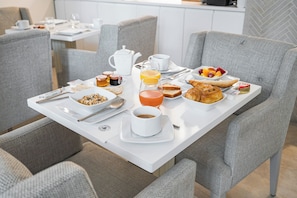 A breakfast table set with a variety of food items including bread, pastries, and a bowl of cereal. - Hôtel Villa d'Estrées - Saint-Germain (Paris)
