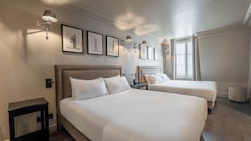 Una habitación de hotel con dos camas, una mesita de noche, una lámpara y cuadros en la pared.