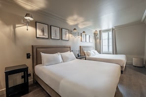 A hotel room with two beds, a nightstand, a lamp, and framed artwork on the wall. - Hôtel Villa d'Estrées - Saint-Germain (Paris)