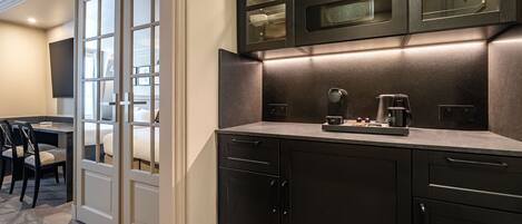A modern kitchen with dark cabinetry, a built-in oven, and a coffee maker on the countertop.
