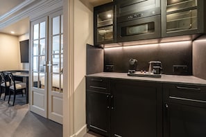 A modern kitchen with dark cabinetry, a built-in oven, and a coffee maker on the countertop.