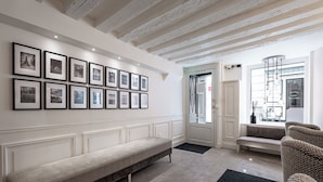 A modern interior with a long bench, a sofa, and a wall adorned with framed photographs. - Hôtel Villa d'Estrées - Saint-Germain (Paris)