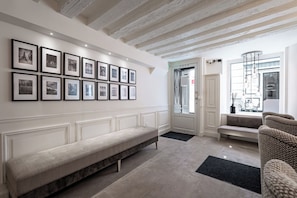 A modern interior with a long bench, a sofa, and a wall adorned with framed photographs. - Hôtel Villa d'Estrées - Saint-Germain (Paris)