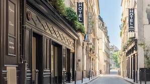 A street view with buildings on either side, each with a 'HOTEL' sign. There are bollards along the sidewalk, and a bicycle is parked on the right. - Hôtel Villa d'Estrées - Saint-Germain (Paris)
