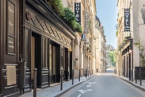 A street view with buildings on either side, each with a 'HOTEL' sign. There are bollards along the sidewalk, and a bicycle is parked on the right. - Hôtel Villa d'Estrées - Saint-Germain (Paris)