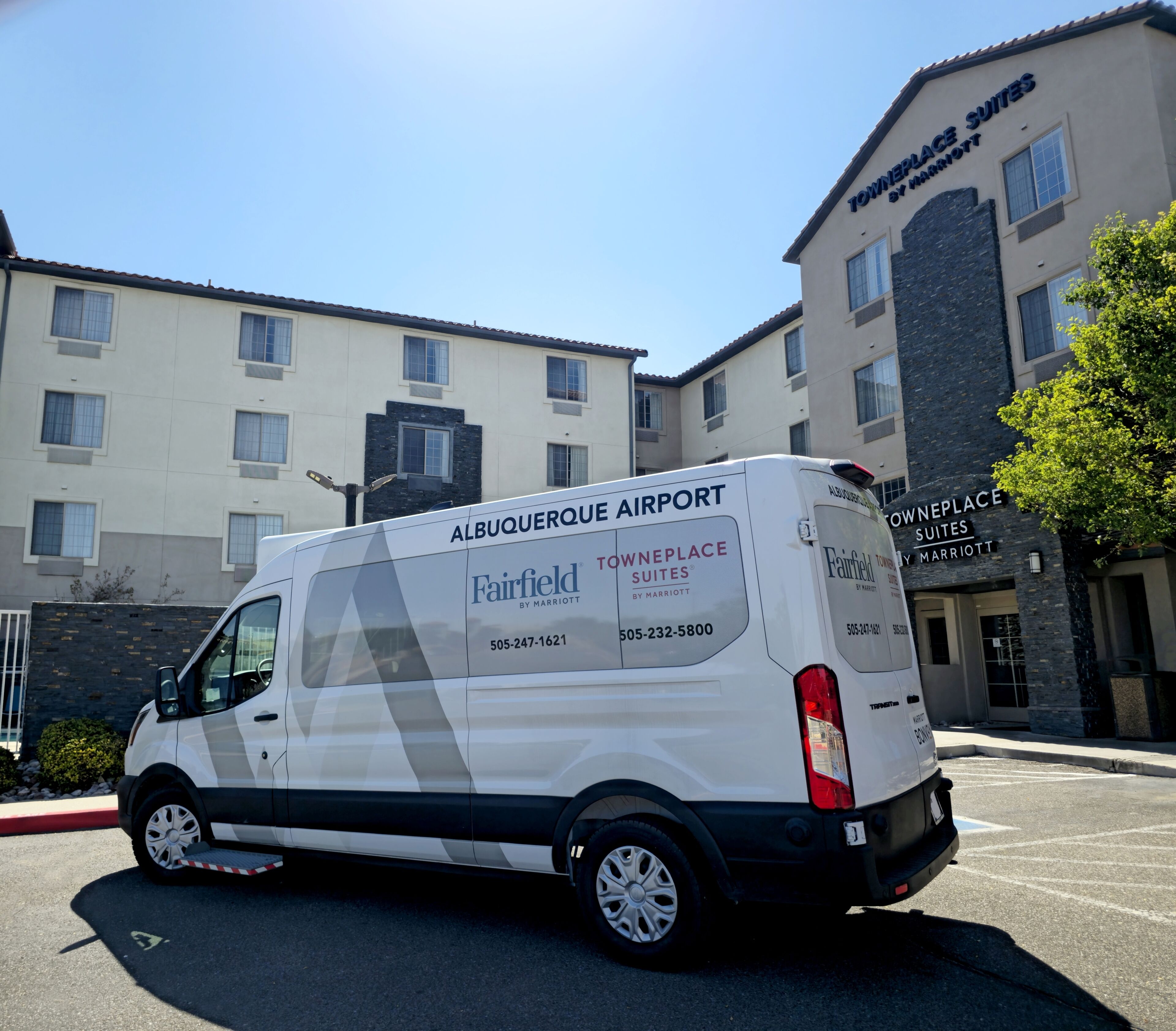 A white van parked in front of a hotel with 'Towneplace Suites by Marriott' signage.