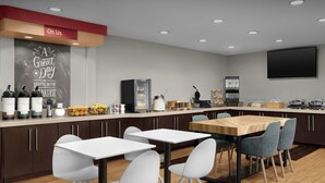 A modern restaurant with a breakfast bar, white chairs, and a large TV screen. - Towneplace Suites Abq Airport (Albuquerque)