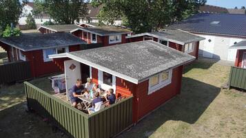 A small, red mobile home with a porch area where a group of people are seated at a table.