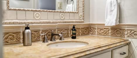 Une salle de bain équipée d’un lavabo, d’un miroir, d’un porte-serviettes et d’une bouteille de shampoing.