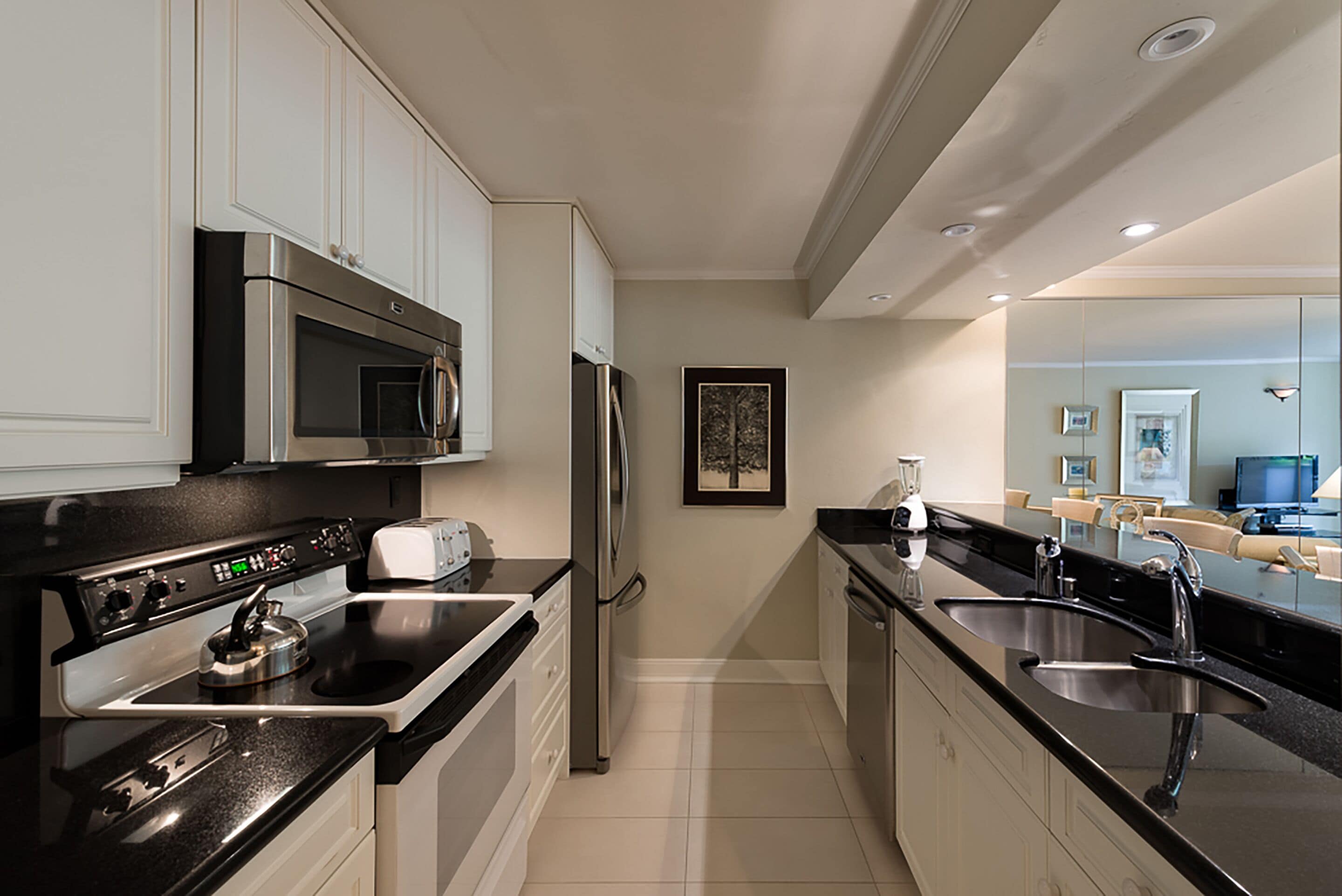 A modern kitchen with stainless steel appliances, a black countertop, and a large island with a sink.