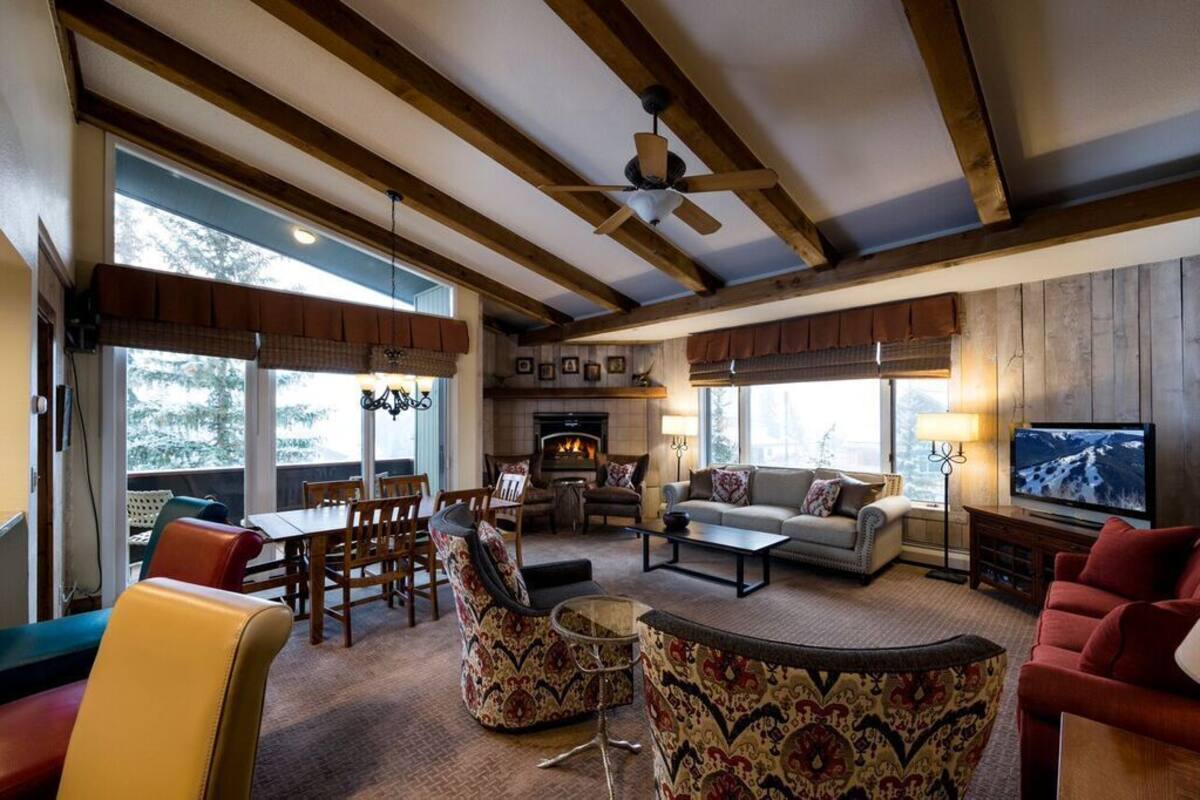 A spacious living room with a fireplace, comfortable seating, and large windows.