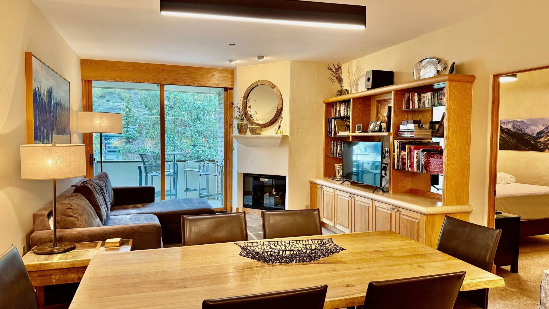 Ein modernes Wohnzimmer mit Kamin, einem Essbereich mit Holztisch und einem Bücherregal voller Bücher.