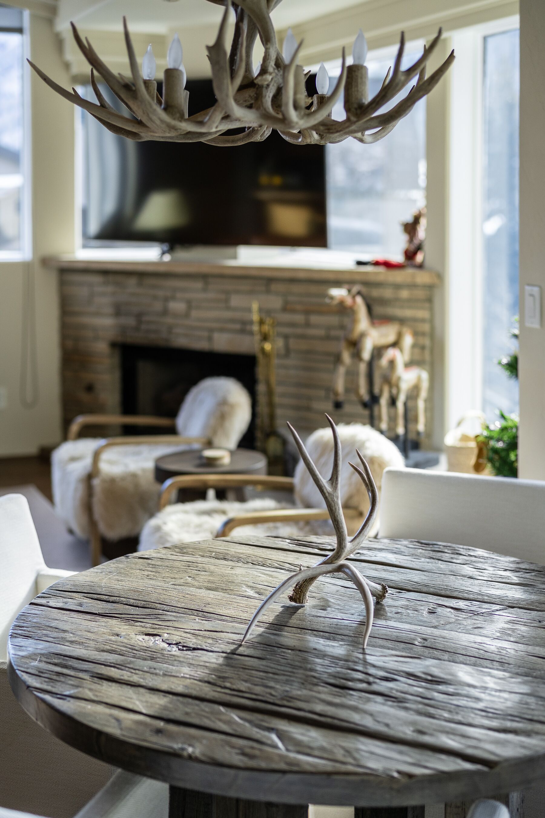 A rustic wooden table with antlers in a cozy living room with a fireplace and comfortable seating.