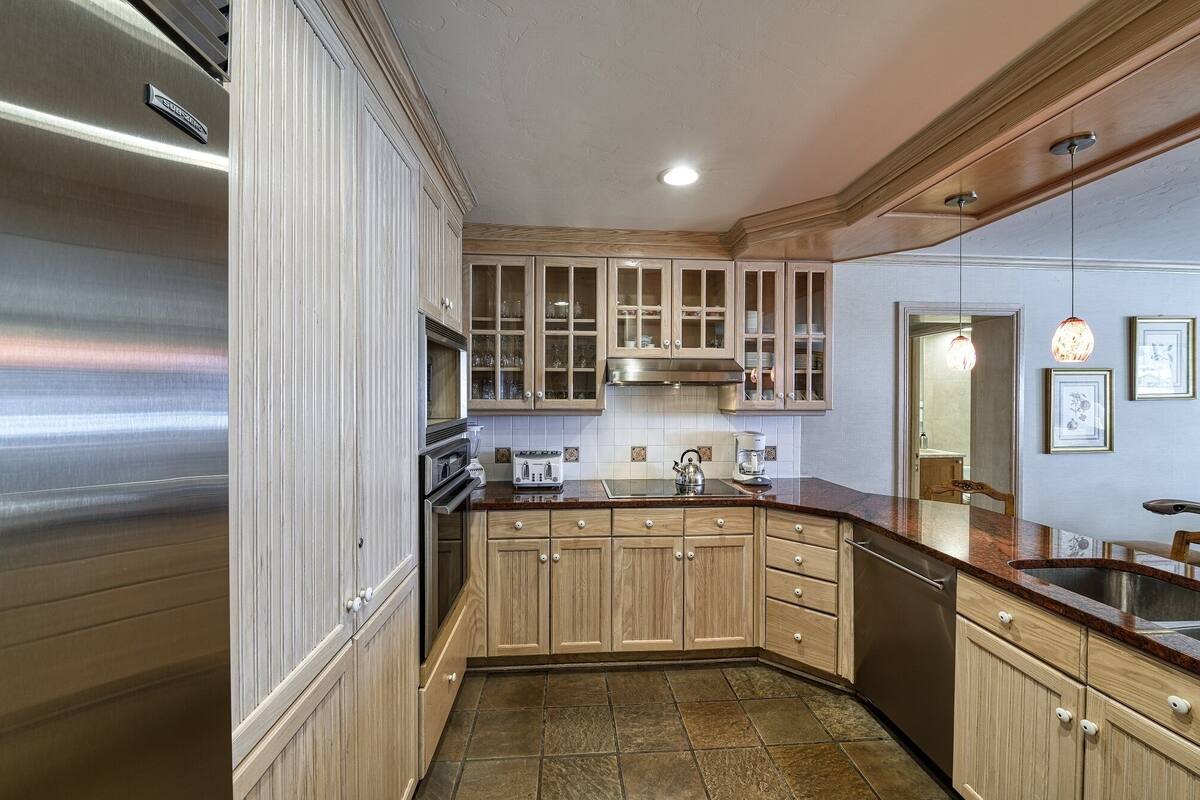 A kitchen with wooden cabinets, a stainless steel refrigerator, a built-in oven, a microwave, and a coffee maker.