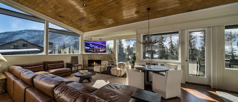 A spacious living room with a leather sofa, a fireplace, and a large TV.