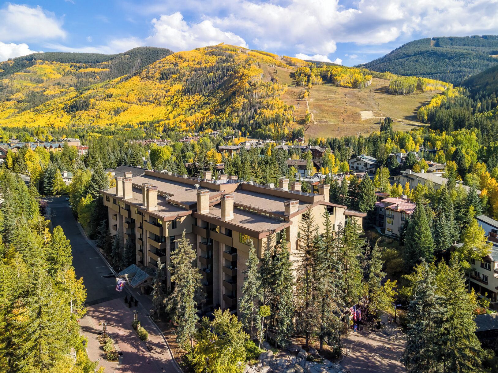 A multi-story hotel with a central courtyard, surrounded by dense forest and hills.