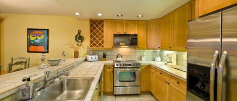 A modern kitchen with wooden cabinets, stainless steel appliances, and a tiled backsplash.